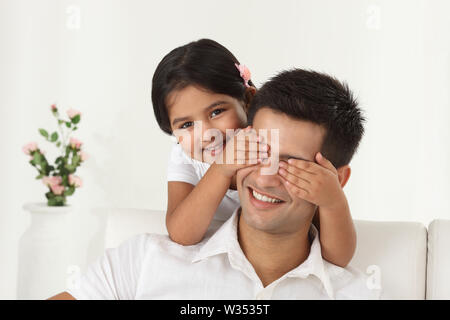 Mädchen, die ihren Vater die Augen von hinten bedeckt Stockfoto