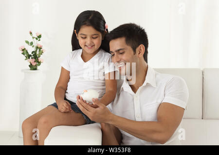 Mädchen hält ein Sparschwein mit ihrem Vater Stockfoto
