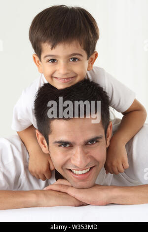 Porträt von einem indischen Mann lächelnd mit seinem Sohn auf dem Bett Stockfoto