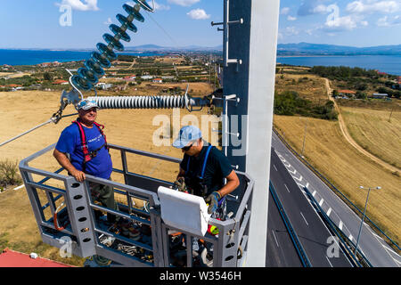 Chalkidiki, Griechenland - Juli 12, 2019: Elektriker sind Klettern auf elektrischen Polen Stromleitungen zu installieren und reparieren Nach dem heftigen Sturm, t Struck Stockfoto