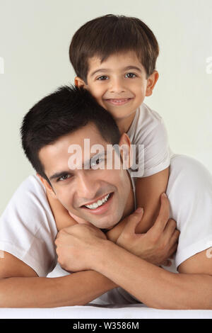 Porträt von einem indischen Mann lächelnd mit seinem Sohn auf dem Bett Stockfoto