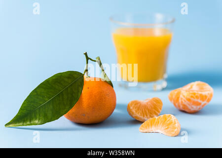 Grünen Clementine, geschält Clementine und Glas clementine Saft auf einem hellblauen Hintergrund Stockfoto