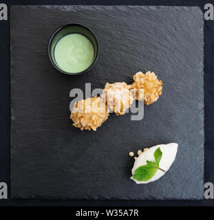 Beliebte asiatische Street Food Pisang Goreng (gebratene Bananen in der knusprigen Reis) in moderner Weise mit Eis und pandan Sauce serviert. Stockfoto