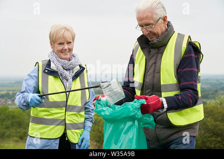Hilfreich Senior Paar sammeln Müll in der Landschaft Stockfoto