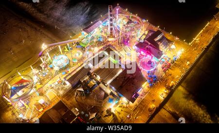 Luftaufnahme eines Karnevals in einem Freizeitpark in der Nähe Der Strand in der Nacht Stockfoto