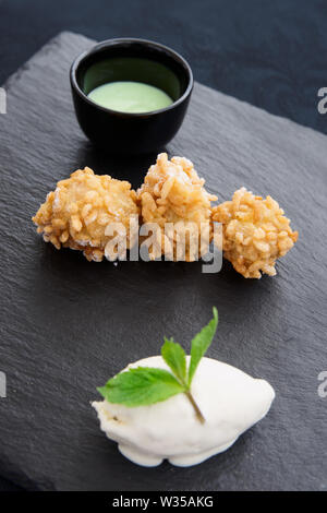 Beliebte asiatische Street Food Pisang Goreng (gebratene Bananen in der knusprigen Reis) in moderner Weise mit Eis und pandan Sauce serviert. Stockfoto