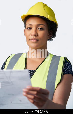 Studio Portrait von weiblichen Architekten mit dem Studieren Pläne gegen den weißen Hintergrund Stockfoto