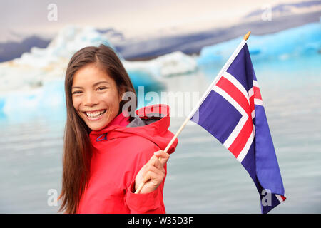 Isländischer Flagge - Mädchen, dass Island Flagge bei Gletscherlagune Jokulsarlon/Gletschersee. Glücklich lächelnde Frau touristische vor eisbergs. Stockfoto