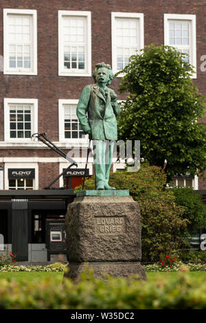 Die Edvard Grieg Statue auf Olav Kyrres Gate im Zentrum von Bergen, Norwegen, mit einer Straßenbahn vorbei im Hintergrund. Stockfoto