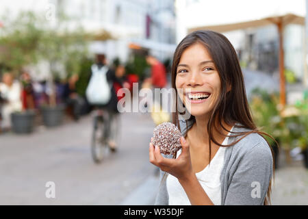 Frau essen traditionelle dänische Küche floedeboller auch als Creme Brötchen oder eibisch teacake. Mädchen genießen die Schokolade im Ort Straße von Kopenhagen, Dänemark. Stockfoto