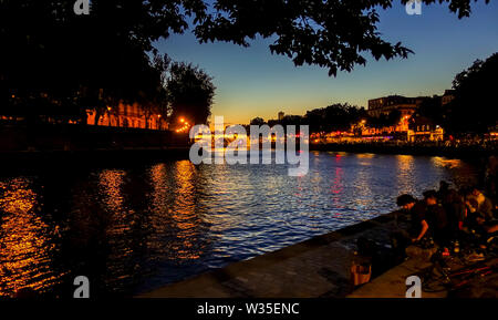 Die Menschen feiern in der Nähe von Pont Marie Brücke bei Nacht beleuchtet Ile Saint Louis, am Fluss Seine, Paris, Frankreich. Stockfoto