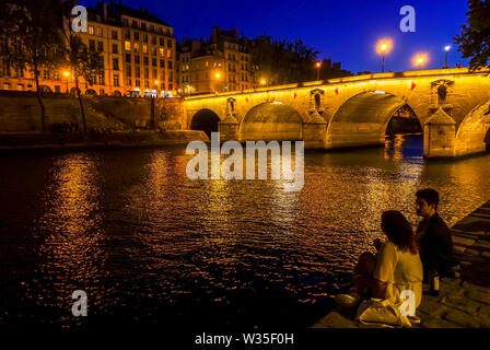 Junges Paar an Pont Marie Brücke bei Nacht beleuchtet Ile Saint Louis, am Fluss Seine, Paris, Frankreich. Stockfoto