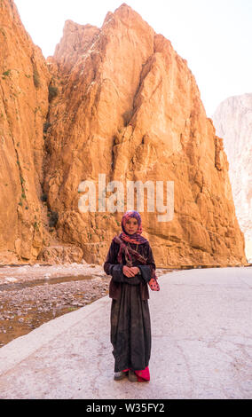 Eine junge traditionellen Berber Mädchen in traditioneller Kleidung in die Dades Schluchten in das Atlasgebirge in Marokko in Nordafrika an der Kamera. Stockfoto