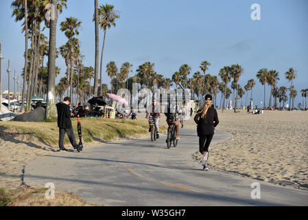 Venedig, CA/USA - Juli 5, 2019: Radfahrer und Roller auf dem Radweg am Strand Venedig Stockfoto