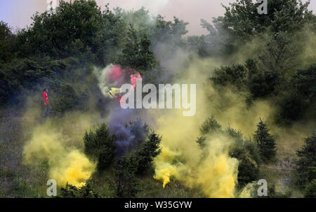 Hardheim, Deutschland. 12. Juli, 2019. Fussball: Test Matches, FC Schweinberg - Borussia Dortmund. Vor dem Spiel außerhalb des Stadions, Fußball Fans Licht bengalischen Feuern in Rot und Gelb. Foto: Karl-Josef Hildenbrand/dpa/Alamy leben Nachrichten Stockfoto