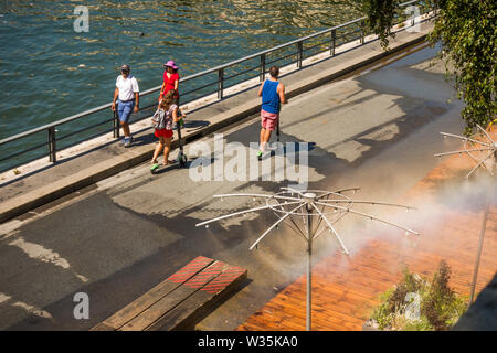 Fußgänger zu Fuß entlang der Seine erste Entlastung von Wasser Sprinkler, während der Hitzewelle. Paris, Frankreich. Stockfoto
