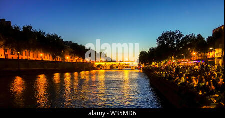Die Menschen feiern in der Nähe von Pont Marie Brücke bei Nacht beleuchtet Ile Saint Louis, am Fluss Seine, Paris, Frankreich. Stockfoto