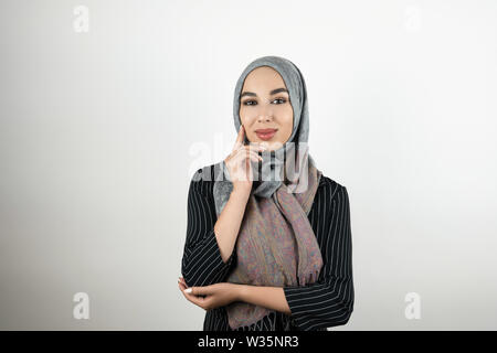 Junge schöne Muslimischen business Frau mit Turban hijab Kopftuch berühren Ihr Gesicht mit einer Hand in stehender Position isoliert weißer Hintergrund Stockfoto