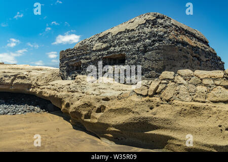 Blick auf die Südküste von El Medano. Alte militärische Bunker mit zwei Schießscharten ragen rechts an der Küste. Strahlend blauen Himmel, flauschigen weissen Wolken in Stockfoto