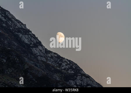 Fast vollen Mond über Felsen steigen in Snowdonia Herbstabend Stockfoto