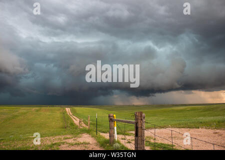 Ein dunkler Sturm taucht am Horizont am Ende der Straße in die Landschaft. Stockfoto