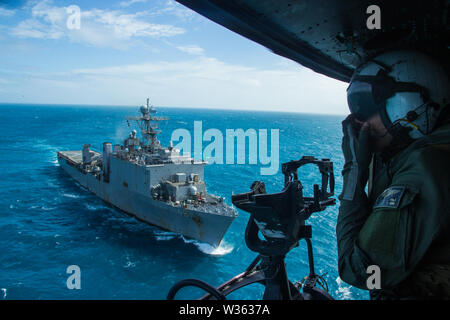 Ein UH-1Y Huey Crew Chief mit Marine Medium Tiltrotor Squadron 265 (verstärkt), 31 Marine Expeditionary Unit, schaut aus einem Huey während eines simulierten besuchen, Board, Durchsuchung und Beschlagnahme des Dock Landung Schiff USS Ashland (LSD 48), unterwegs in der Coral Sea, 7. Juli 2019. Ashland, Teil der Wasp amphibischen bereit, Gruppe, mit Eingeschifft 31 MEU, arbeitet in der indopazifischen Region Interoperabilität mit Partnern zu verbessern und dienen als ready-Response Force für jede Art von Kontingenz, und stellen gleichzeitig eine flexible und tödliche Krise Response Force bereit, eine breite Palette von durchführen Stockfoto