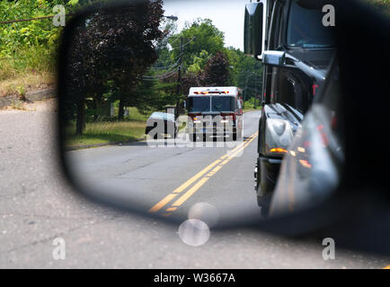 Middletown, CT USA. Auto Seite Spiegel Ansicht der Fahrzeuge über Ziehen für eine schnelle fire truck Reaktion auf einen Notfall. Stockfoto