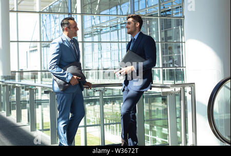 Kaukasische männliche Führungskräfte miteinander interagieren, während im modernen Büro Stockfoto