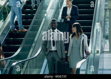 Diverse Geschäftsleute interagieren während der Verwendung von Fahrtreppen in modernen Büro Stockfoto