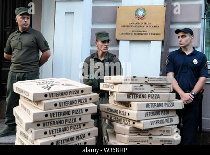 Kiew, Ukraine. 12. Juli, 2019. Polizeibeamte stehen neben einer Barrikade von pizzakartons von Aktivisten platziert bei einer Rallye die Freilassung der Ukrainischen serviceman Vitaly Markiv, außerhalb der Botschaft von Italien in Kiew, Ukraine. Ein italienisches Gericht hat Ukrainischen ehemaligen National Guard Commander, Vitaliy Markiv verurteilt zu 24 Jahren Haft für den Mord an einer Fotografin Andrea Rocchelli und seine russischen übersetzer und Assistant Andrei Mironov in den frühen Tagen des Krieges im Osten der Ukraine im Mai 2014, zwischen der Regierung und der pro-russischen Separatisten. Credit: SOPA Bilder Li Stockfoto