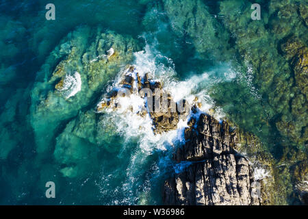 Ansicht von oben, atemberaubenden Blick auf einige Wellen, die auf einer felsigen Küste während ein windiger Tag in Sardinien, Italien. Stockfoto