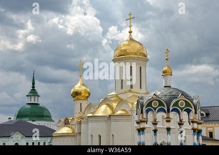 = Kloster Kuppeln und Türme gegen die grauen Wolken = Das leuchtende schöne Kuppeln, Türme und Dächer der Heiligen Trinity-St. Sergius Lavra in Sergiyev Stockfoto