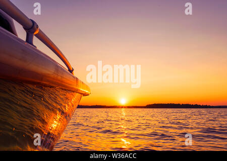 Seitenansicht Beschleunigung angeln Motorboot mit Tropfen Wasser. Blue Ocean Meer Wasser Welle Reflexionen an den Sonnenuntergang. Motorboot im blauen Ozean. Ozean ya Stockfoto
