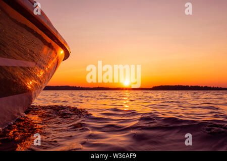 Seitenansicht Beschleunigung angeln Motorboot mit Tropfen Wasser. Blue Ocean Meer Wasser Welle Reflexionen an den Sonnenuntergang. Motorboot im blauen Ozean. Ozean ya Stockfoto