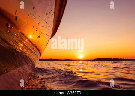 Seitenansicht Beschleunigung angeln Motorboot mit Tropfen Wasser. Blue Ocean Meer Wasser Welle Reflexionen an den Sonnenuntergang. Motorboot im blauen Ozean. Ozean ya Stockfoto