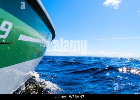 Seitenansicht Beschleunigung angeln Motorboot mit Tropfen Wasser. Blue Ocean Meer Wasser Welle Reflexionen an den Sonnenuntergang. Motorboot im blauen Ozean. Ozean ya Stockfoto