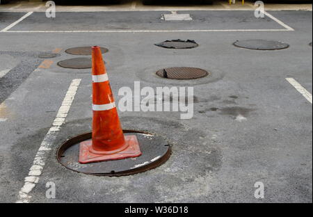 Nahaufnahme des alten Leitkegel auf beschädigt Kanaldeckel, Sicherheitskonzept Stockfoto