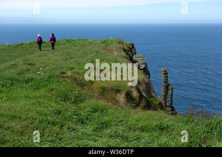 Zwei Frau Wanderungen in den Schornstein Oberteilen auf Causeway Coastal Weg des Riesen, County Antrim, Nordirland, Großbritannien Stockfoto