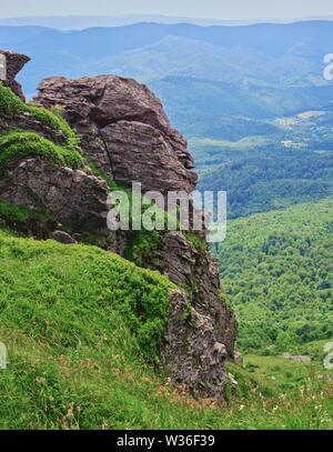 Felsen auf Pikuy Berg gegen das Tal unter majestätischen Green mountain Hills in Wiesen und Wald bedeckt. Bewölkt Sommer Tag im Sommer. Ukraine, Lv Stockfoto