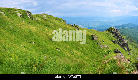 Felsen auf Pikuy Berg gegen das Tal unter majestätischen Green mountain Hills in Wiesen und Wald bedeckt. Bewölkt Sommer Tag im Sommer. Ukraine, Lv Stockfoto