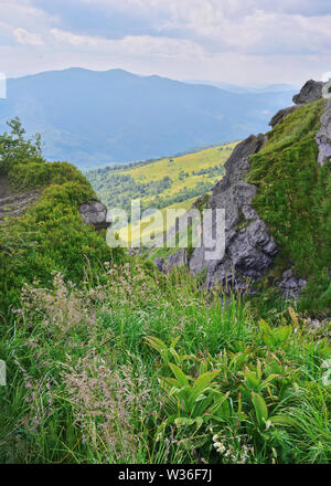 Felsen auf Pikuy Berg gegen das Tal unter majestätischen Green mountain Hills in Wiesen und Wald bedeckt. Bewölkt Sommer Tag im Sommer. Ukraine, Lv Stockfoto