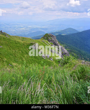 Felsen auf Pikuy Berg gegen das Tal unter majestätischen Green mountain Hills in Wiesen und Wald bedeckt. Bewölkt Sommer Tag im Sommer. Ukraine, Lv Stockfoto