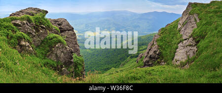 Panorama der Felsen auf Pikuy Berg gegen das Tal unter majestätischen Green mountain Hills in Wiesen und Wald bedeckt. Bewölkt Sommer Tag im Sommer. Stockfoto