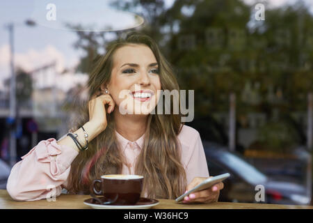 Attraktive junge Frau auf der Suche durch das Fenster im Cafe Stockfoto