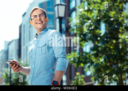 Gut aussehender Geschäftsmann breit grinsend, während Sie am Wochenende zu Fuß Stockfoto