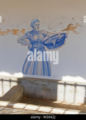 Eine Darstellung einer portugiesischen Frau, die ihr Wäsche in einem Korb über der Leere Holz- Becken eines Alten öffentlichen Waschhaus in Estoi, Portugal. Stockfoto