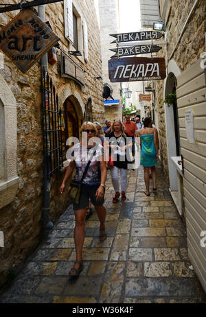 Touristen zu Fuß durch die engen Gassen der Altstadt von Budva, Montenegro. Stockfoto