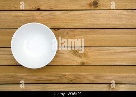 Nahaufnahme von einem leeren weißen Schüssel auf einen Holztisch - direkt über. Stockfoto