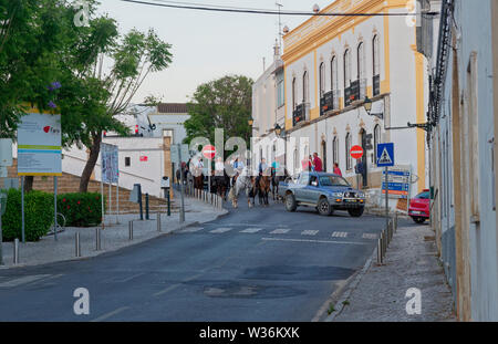 Reiter und ihre Pferde unter der Leitung von einem Toyota Pick Up Van in den Straßen von Estoi an einem frühen Abend in ungezwungener Prozession. Portugal Stockfoto