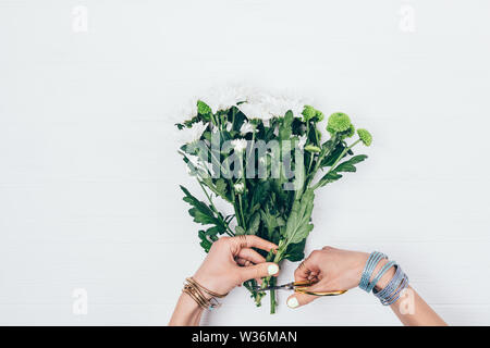 Ansicht von oben weibliche Hände mit einer Schere schneiden stammt von Blumen frischen Blumenstrauß zu machen, flach auf weißem Hintergrund legen. Stockfoto